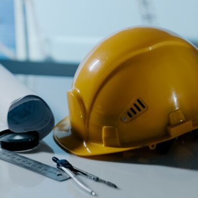 Yellow helmet hat in the project at construction site building oт a table. Building concept. Vertical image.